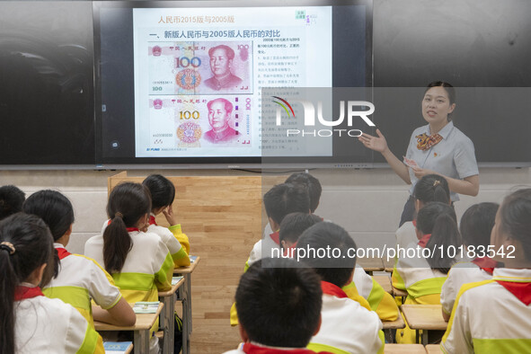 A staff member of China Construction Bank publicized anti fake RMB knowledge to students in Nantong, Jiangsu Province, China, on June 19, 20...