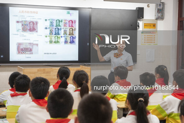 A staff member of China Construction Bank publicized anti fake RMB knowledge to students in Nantong, Jiangsu Province, China, on June 19, 20...