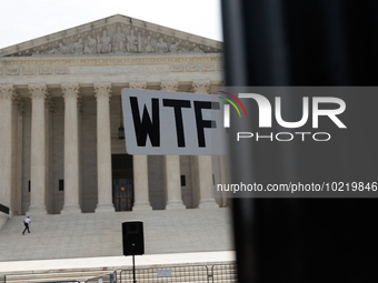 A demonstrator passes the Supreme Court with a sign in Washington, D.C. on June 30, 2023 following the Supreme Court's ruling that President...