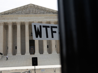 A demonstrator passes the Supreme Court with a sign in Washington, D.C. on June 30, 2023 following the Supreme Court's ruling that President...