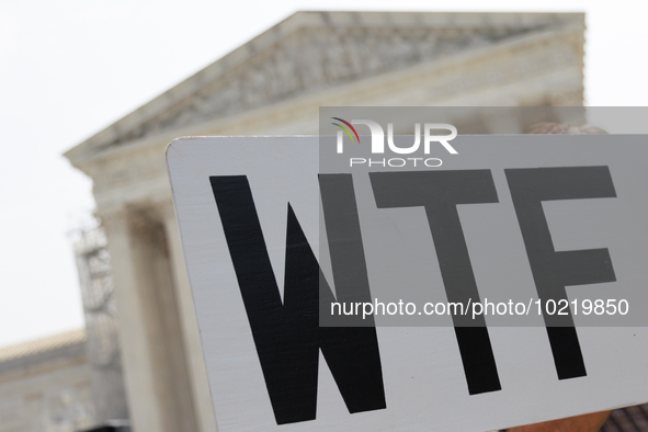 A demonstrator passes the Supreme Court with a sign in Washington, D.C. on June 30, 2023 following the Supreme Court's ruling that President...