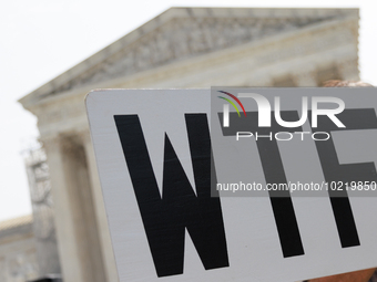 A demonstrator passes the Supreme Court with a sign in Washington, D.C. on June 30, 2023 following the Supreme Court's ruling that President...