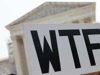 A demonstrator passes the Supreme Court with a sign in Washington, D.C. on June 30, 2023 following the Supreme Court's ruling that President...