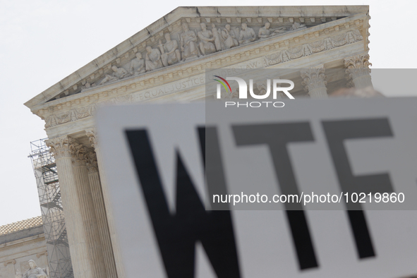 A demonstrator passes the Supreme Court with a sign in Washington, D.C. on June 30, 2023 following the Supreme Court's ruling that President...