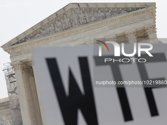 A demonstrator passes the Supreme Court with a sign in Washington, D.C. on June 30, 2023 following the Supreme Court's ruling that President...