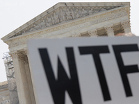 A demonstrator passes the Supreme Court with a sign in Washington, D.C. on June 30, 2023 following the Supreme Court's ruling that President...