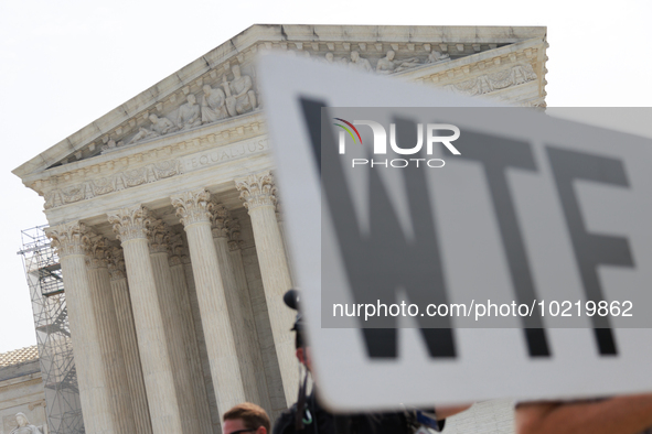 A demonstrator passes the Supreme Court with a sign in Washington, D.C. on June 30, 2023 following the Supreme Court's ruling that President...