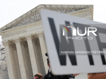 A demonstrator passes the Supreme Court with a sign in Washington, D.C. on June 30, 2023 following the Supreme Court's ruling that President...