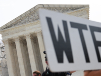 A demonstrator passes the Supreme Court with a sign in Washington, D.C. on June 30, 2023 following the Supreme Court's ruling that President...