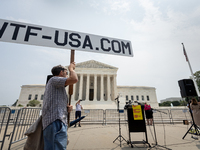 A conspiracy theorist stands in front of Supreme Court prior to a protest of the Court's ruling against President Joe Biden’s student-debt r...