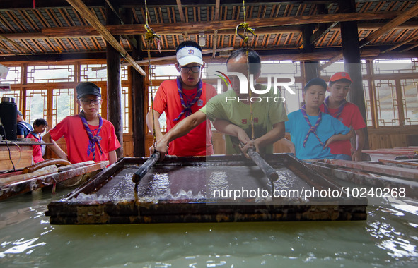 

An inheritor of intangible cultural heritage (3rd R) is guiding primary school students on a study tour to experience ancient papermaking...