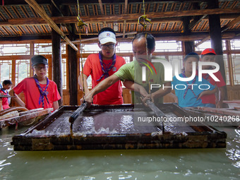 

An inheritor of intangible cultural heritage (3rd R) is guiding primary school students on a study tour to experience ancient papermaking...