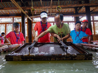 

An inheritor of intangible cultural heritage (3rd R) is guiding primary school students on a study tour to experience ancient papermaking...