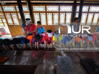 

Primary school students from Shanghai are experiencing ancient papermaking skills in Shiqiao Village, Nangao Township, Danzhai County, Qia...