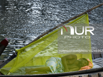 A boatman sleeps under a mosquito net on his boat to protect himself from dengue at the bank of the Buriganga River in Dhaka, Bangladesh, on...