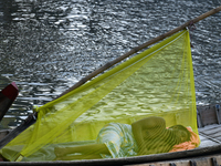 A boatman sleeps under a mosquito net on his boat to protect himself from dengue at the bank of the Buriganga River in Dhaka, Bangladesh, on...