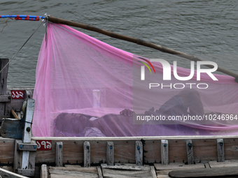 A boatman sleeps under a mosquito net on his boat to protect himself from dengue at the bank of the Buriganga River in Dhaka, Bangladesh, on...