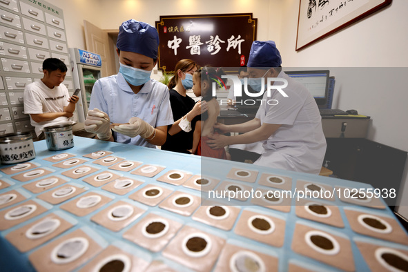 

A doctor at a traditional Chinese medicine clinic is applying "Sanfu stickers" to a child in Zaozhuang, Shandong Province, China on July 1...