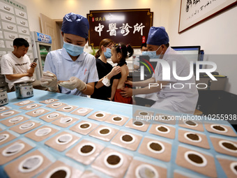 

A doctor at a traditional Chinese medicine clinic is applying "Sanfu stickers" to a child in Zaozhuang, Shandong Province, China on July 1...