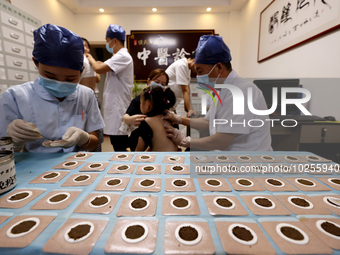 

A doctor at a traditional Chinese medicine clinic is applying "Sanfu stickers" to a child in Zaozhuang, Shandong Province, China on July 1...