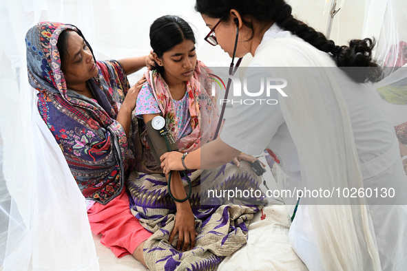 A Doctor treats a patient covered with mosquito nets who are suffering from dengue fever rest inside the 'Shaheed Suhrawardy' Medical Collea...