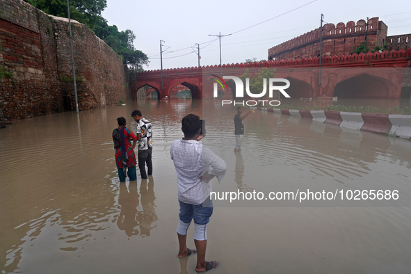 People click pictures near a flooded bridge behind the iconic Red Fort, after a rise in the waters of the river Yamuna due to heavy monsoon...