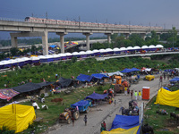 A metro train moves on a bridge as residents take shelter in a relief camp, after a rise in the waters of river Yamuna due to heavy monsoon...