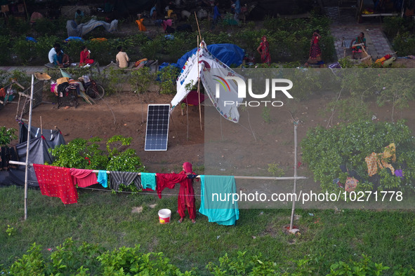 A woman dries clothes outside a makeshift tent as residents take shelter under a flyover, after a rise in the waters of river Yamuna due to...