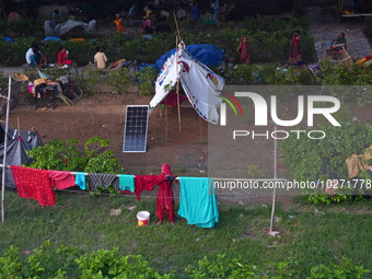 A woman dries clothes outside a makeshift tent as residents take shelter under a flyover, after a rise in the waters of river Yamuna due to...