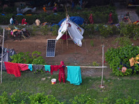 A woman dries clothes outside a makeshift tent as residents take shelter under a flyover, after a rise in the waters of river Yamuna due to...