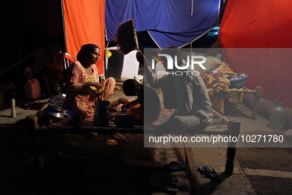 A family eats food outside a makeshift tent as they take shelter on an under-construction flyover, after a rise in the waters of river Yamun...