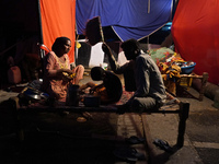 A family eats food outside a makeshift tent as they take shelter on an under-construction flyover, after a rise in the waters of river Yamun...