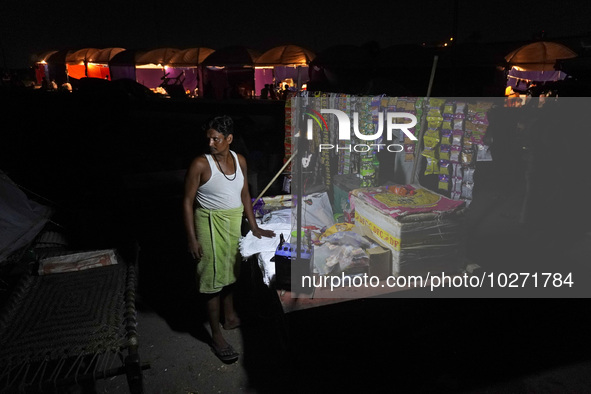 A man stands at his temporary shop set-up near the makeshift tents for evacuated residents on an elevated road, after a rise in the waters o...