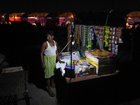 A man stands at his temporary shop set-up near the makeshift tents for evacuated residents on an elevated road, after a rise in the waters o...