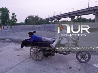 Men rest on a rickshaw near the makeshift tents for evacuated residents on an under-construction flyover, after a rise in the waters of rive...