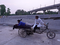 Men rest on a rickshaw near the makeshift tents for evacuated residents on an under-construction flyover, after a rise in the waters of rive...