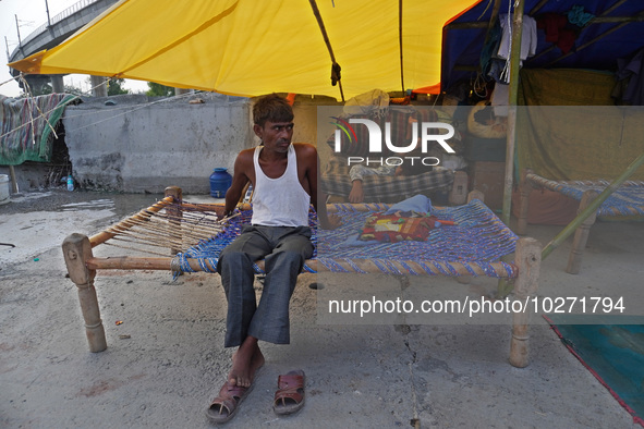 A man sits in a makeshift tent for evacuated residents on an under-construction flyover, after a rise in the waters of river Yamuna due to h...