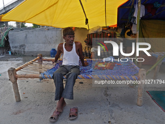 A man sits in a makeshift tent for evacuated residents on an under-construction flyover, after a rise in the waters of river Yamuna due to h...