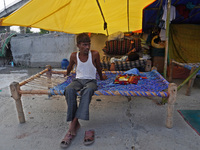 A man sits in a makeshift tent for evacuated residents on an under-construction flyover, after a rise in the waters of river Yamuna due to h...