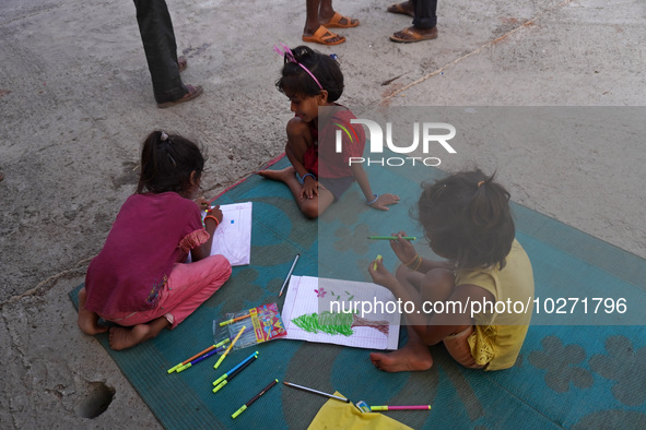 Children make drawings in their notebooks outside a makeshift tent for evacuated residents on an under-construction flyover, after a rise in...