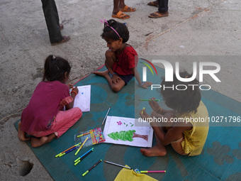 Children make drawings in their notebooks outside a makeshift tent for evacuated residents on an under-construction flyover, after a rise in...