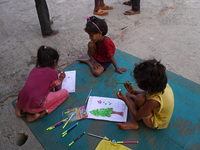 Children make drawings in their notebooks outside a makeshift tent for evacuated residents on an under-construction flyover, after a rise in...