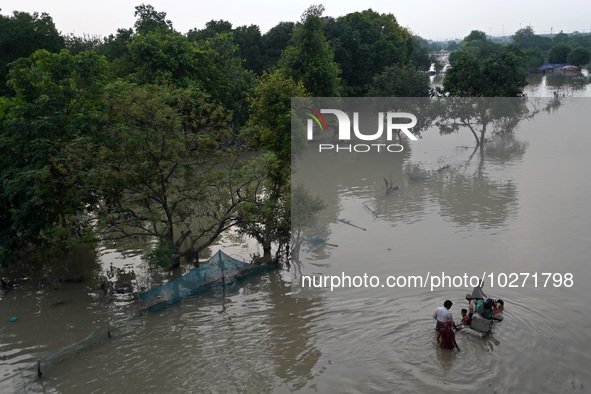 A family with their belongings wades through the flooded waters in a low-lying area, after a rise in the waters of river Yamuna due to heavy...