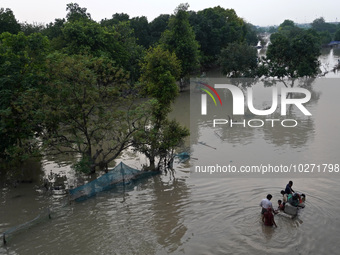 A family with their belongings wades through the flooded waters in a low-lying area, after a rise in the waters of river Yamuna due to heavy...