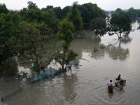 A family with their belongings wades through the flooded waters in a low-lying area, after a rise in the waters of river Yamuna due to heavy...