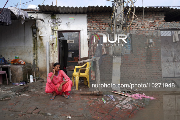 A woman sits outside her flooded house in a low-lying area, after a rise in the waters of river Yamuna due to heavy monsoon rains, in New De...