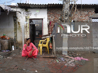 A woman sits outside her flooded house in a low-lying area, after a rise in the waters of river Yamuna due to heavy monsoon rains, in New De...