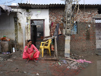 A woman sits outside her flooded house in a low-lying area, after a rise in the waters of river Yamuna due to heavy monsoon rains, in New De...