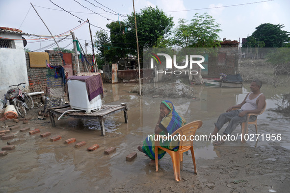 A couple sits outside their flooded house inside a waterlogged street in a low-lying area, after a rise in the waters of river Yamuna due to...