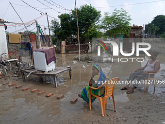 A couple sits outside their flooded house inside a waterlogged street in a low-lying area, after a rise in the waters of river Yamuna due to...